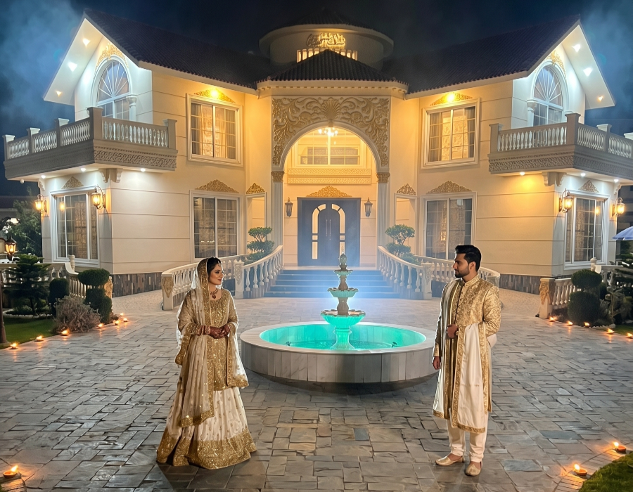 Couple in traditional attire posing at a luxury farmhouse with fountain during a romantic anniversary photoshoot in Islamabad at night