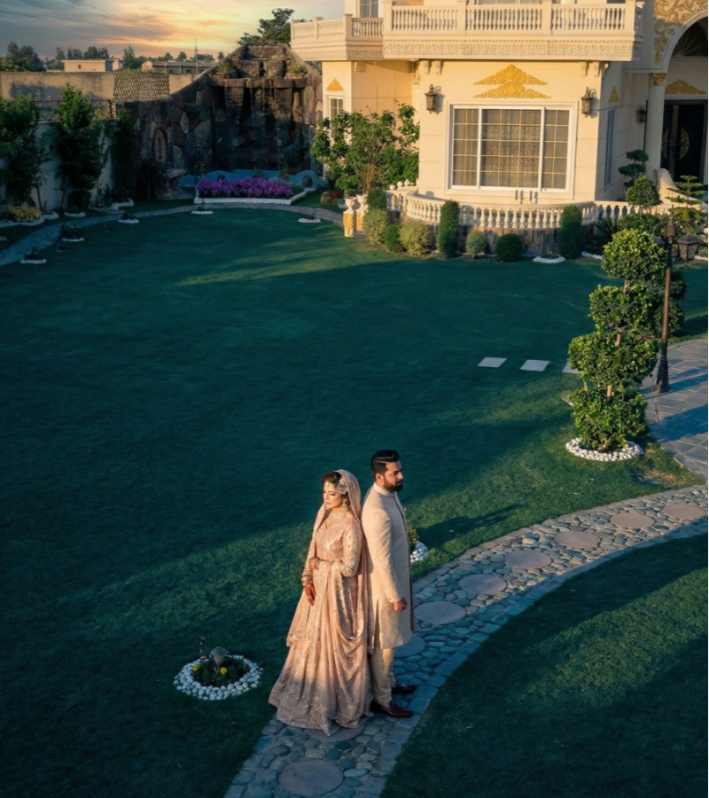 Couple posing on garden pathway at luxury photoshoot venue near Islamabad with elegant lawn and sunset backdrop