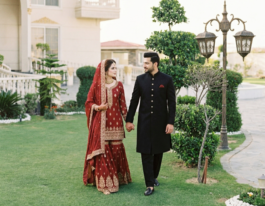 Couple in traditional attire walking in scenic resort garden, premium private photoshoot venue in Islamabad with lush outdoor setting