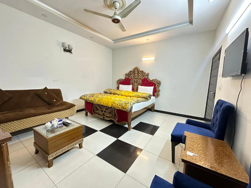 Spacious guest house room in Islamabad with ornate bed, seating area, modern furnishings, and bright lighting for a comfortable stay in 2026.